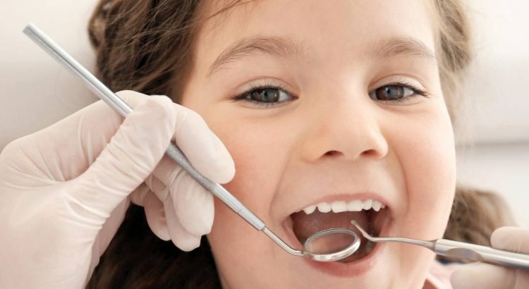 Criança na primeira consulta ao dentista com acompanhamento dos pais