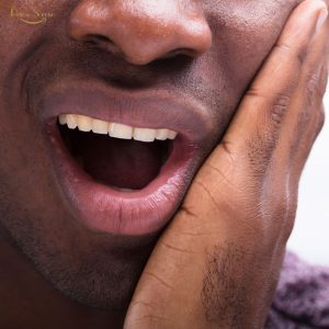 Pessoa com dor de dente durante a noite segurando o rosto