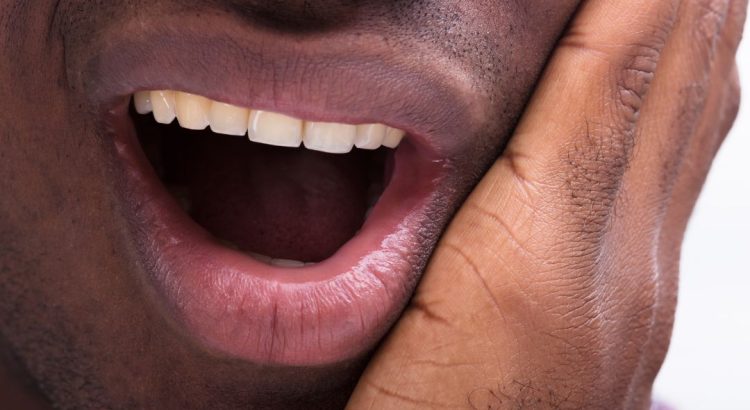 Pessoa com dor de dente durante a noite segurando o rosto
